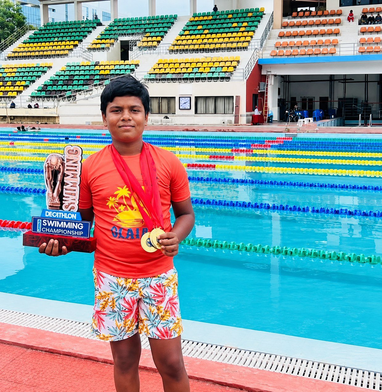 Young swimmer celebrating a championship win with medals and trophy