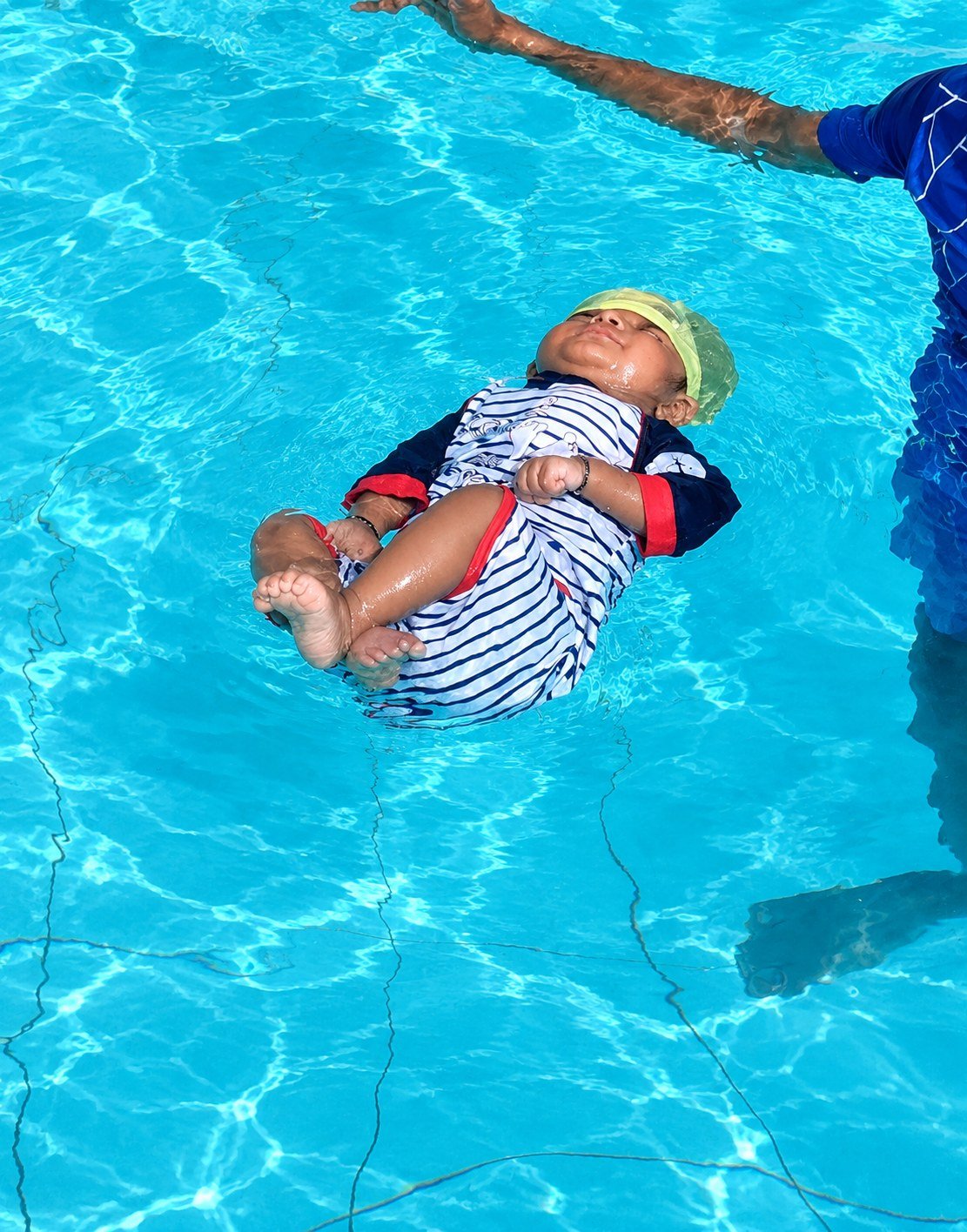Parent holding a toddler with a float in the pool
